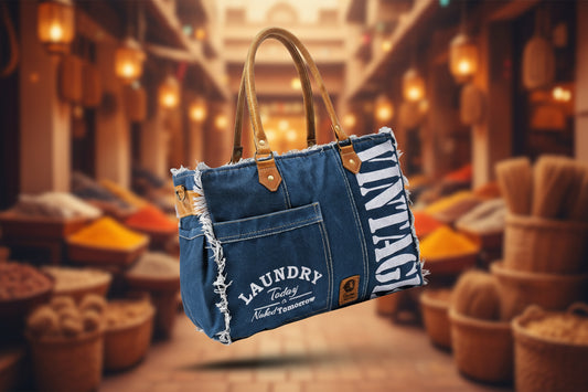 Blue denim handbag with brown handles on a light gray background, featuring the brand 'Qyuum'.